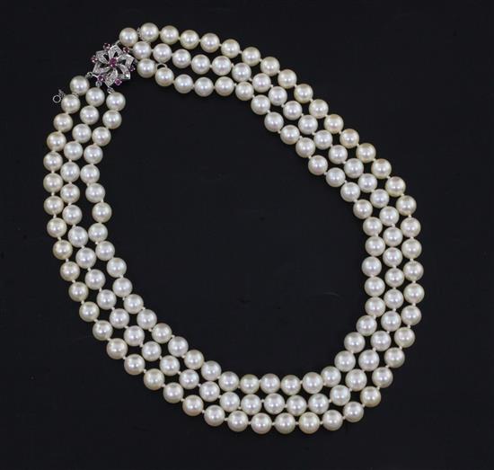 A three-strand uniform cultured pearl necklace with ruby, diamond and white gold (tests as 9ct) openwork flowerhead clasp, 40.5cm.